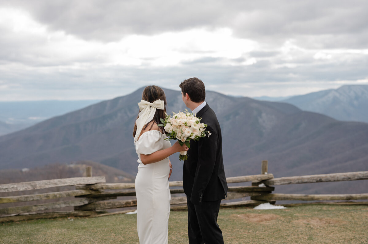 a bride and groom overlook the mountains at wintergreen resort on an overcast winter day