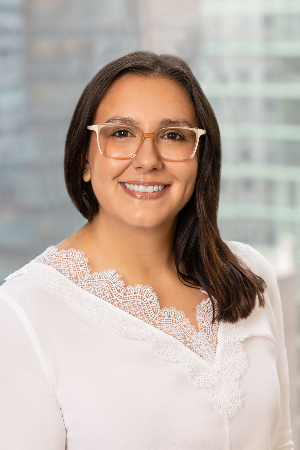 Woman in glasses and white blouse smiling indoors