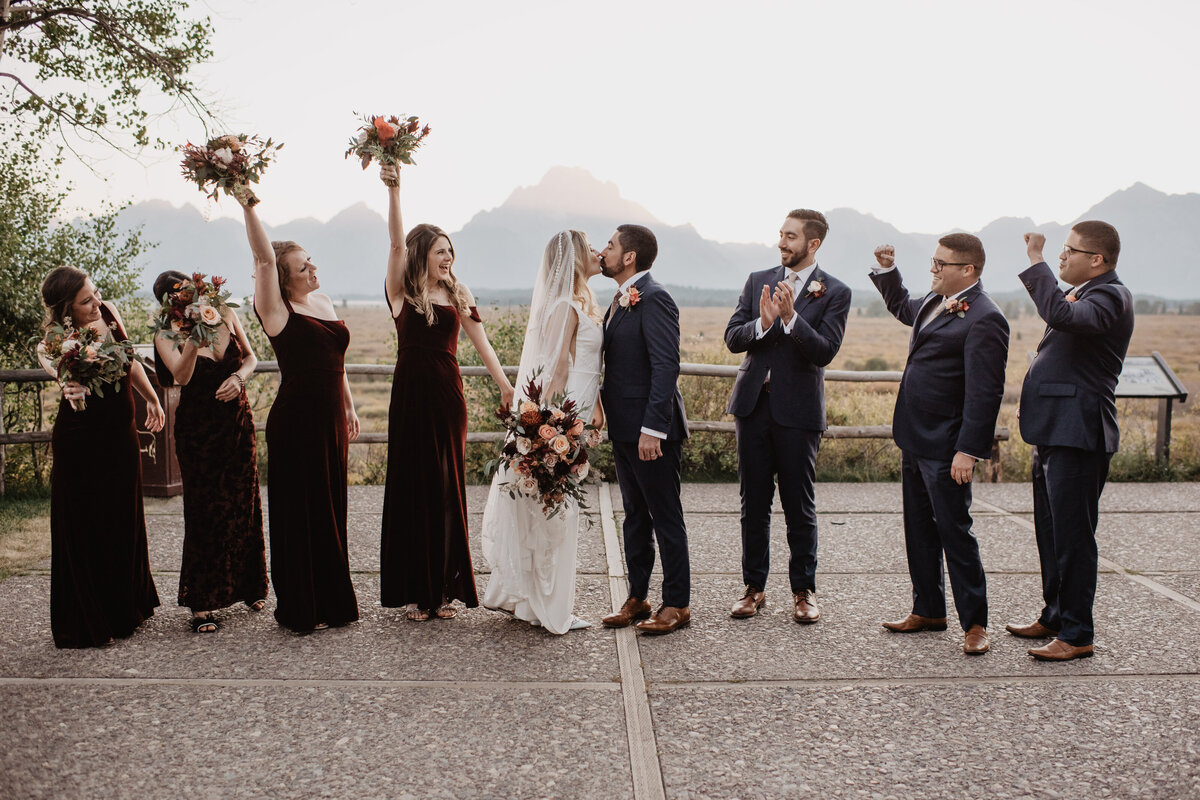 Photographers Jackson Hole captures couple kissing while wedding party celebrates