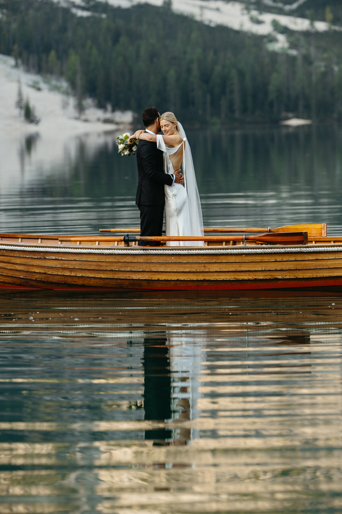 Couple holding each other in boat with lake reflections