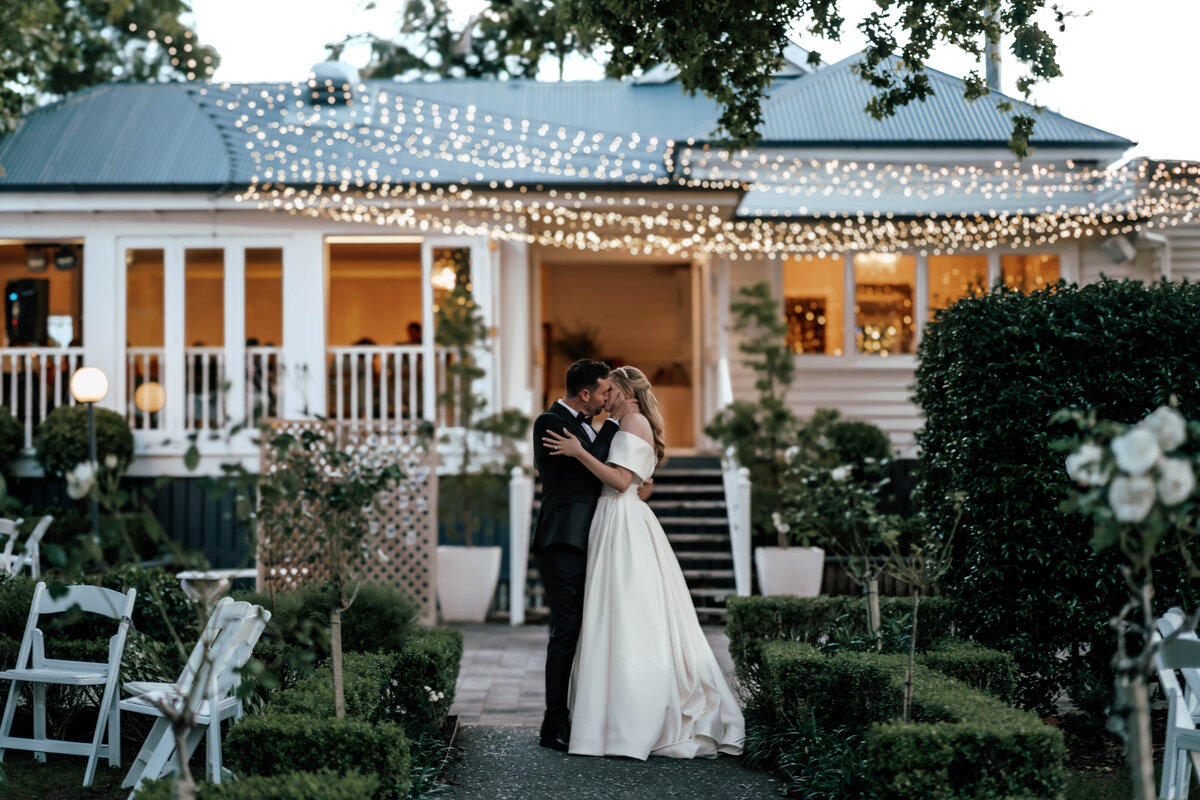 Holly and Shane standing together outside their Auckland wedding venue, photographed by Zanthe Vorsatz.