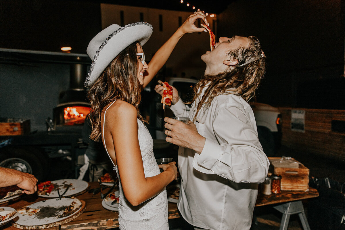 bride and groom share pizza at wedding reception in san diego