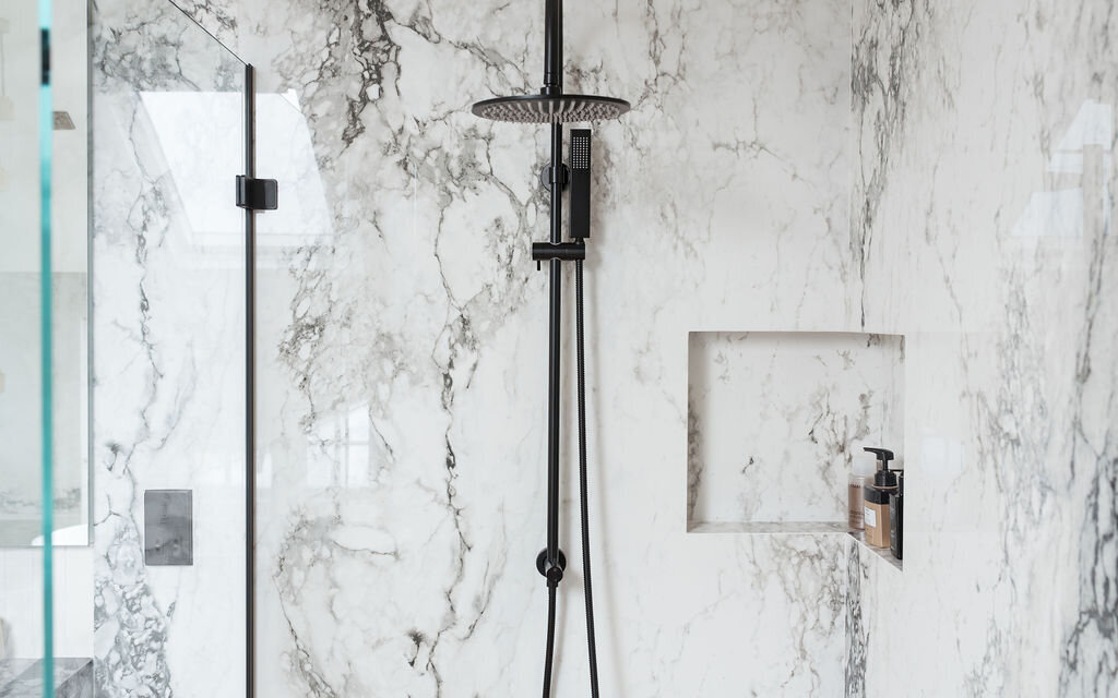 A modern white and grey marble glass-enclosed shower with matte black hardware.