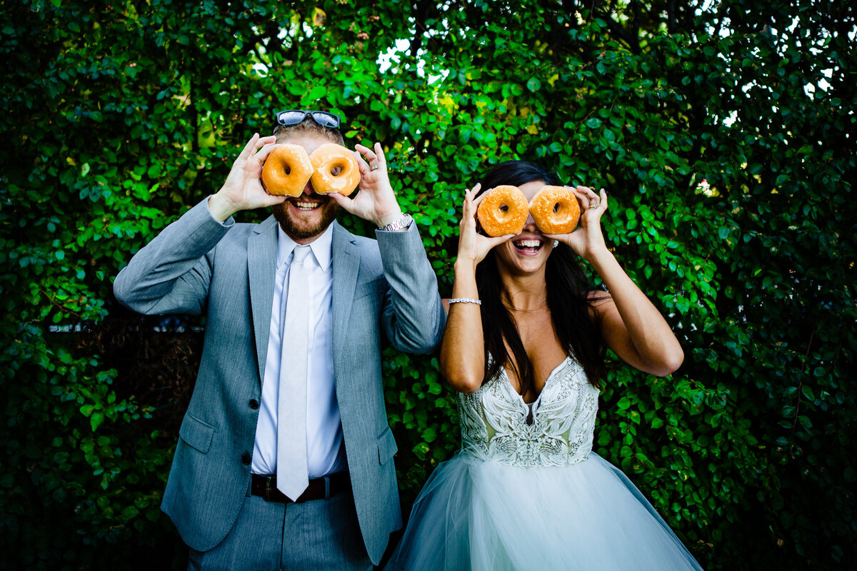 One of the top wedding photos of 2020. Taken by Adore Wedding Photography- Toledo, Ohio Wedding Photographers. This fun photo is of a bride and groom holding donuts over their eyes