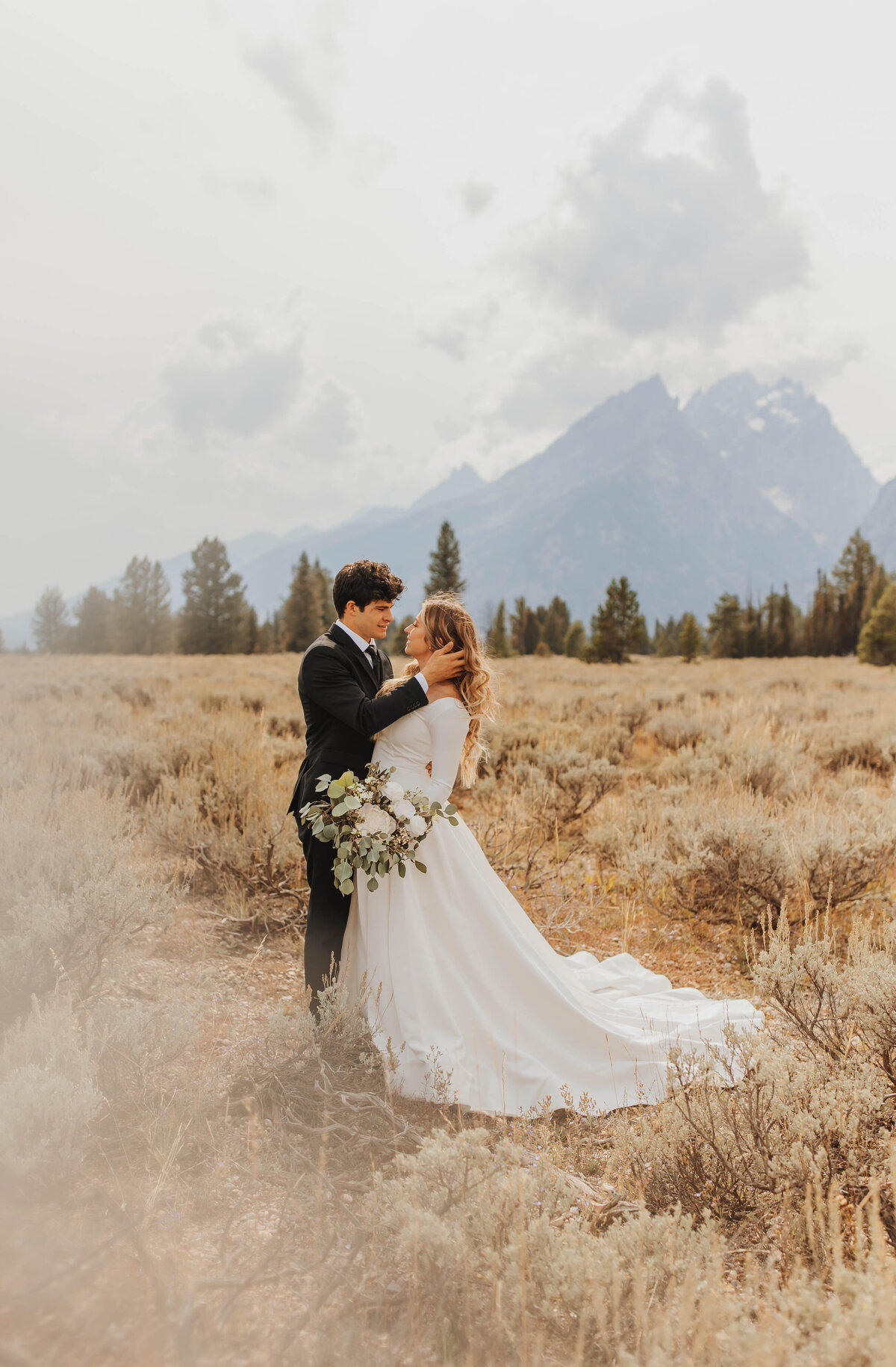 bride and groom embracing in field