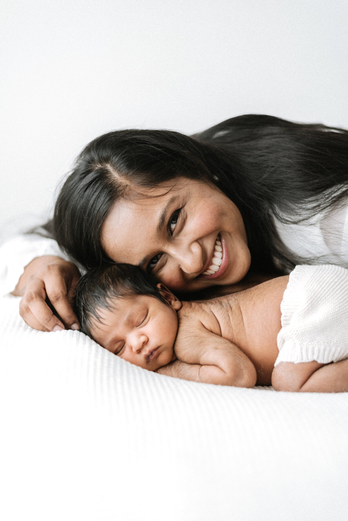 Mum smiling next to newborn daughter at Billingshurst newborn photoshoot