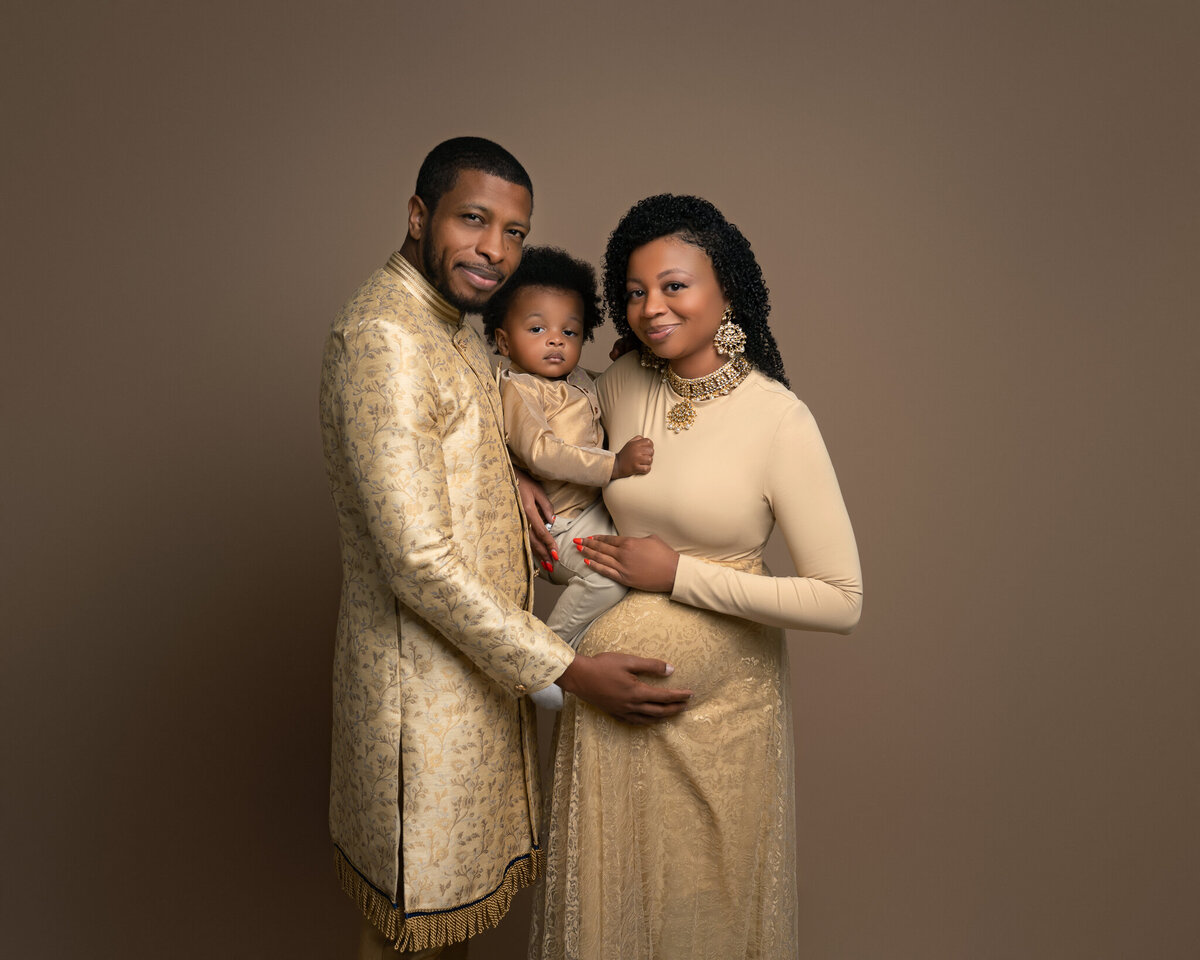 Elegant family maternity photo with gold outfits, taken in a Westlake studio near Austin, TX.
