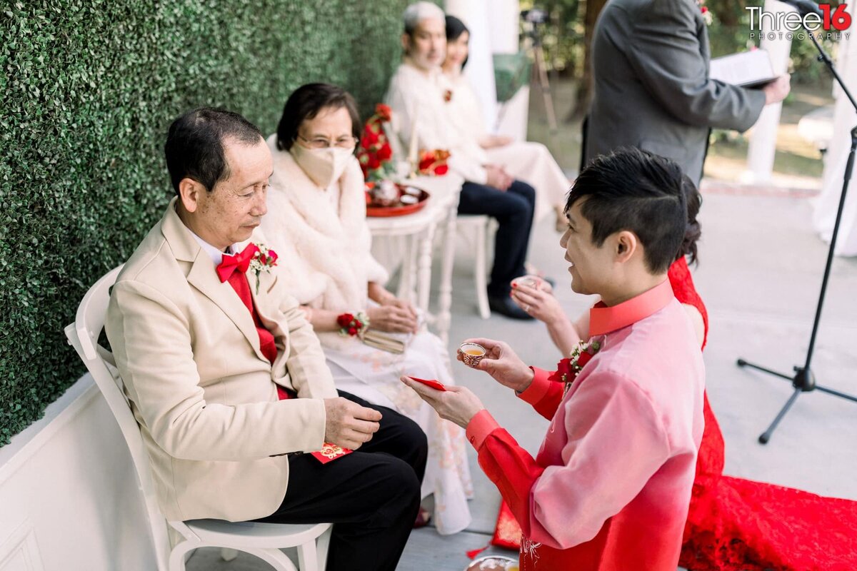 While on their knees the Bride and Groom present tea to the parents as part of the Chinese Wedding Ceremony