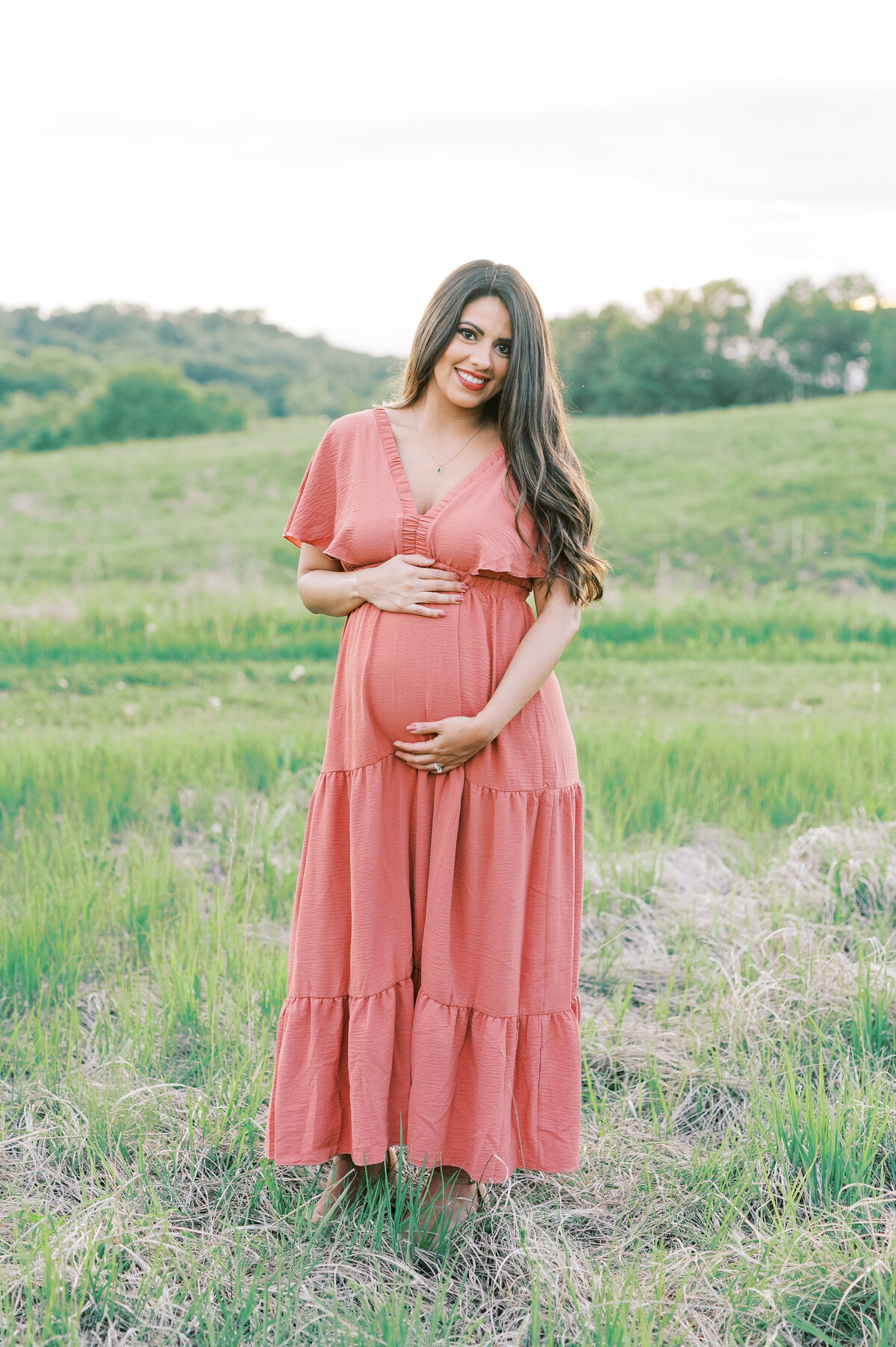 Mom in field holding stomach at maternity session