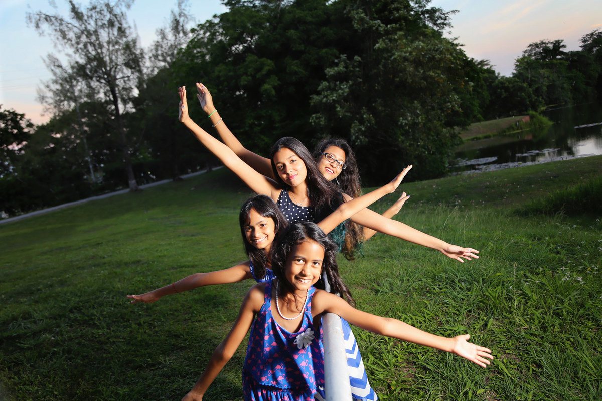young girls in playful pose with outstretched hands in park. Photo by Ross Photography, Trinidad, W.I..