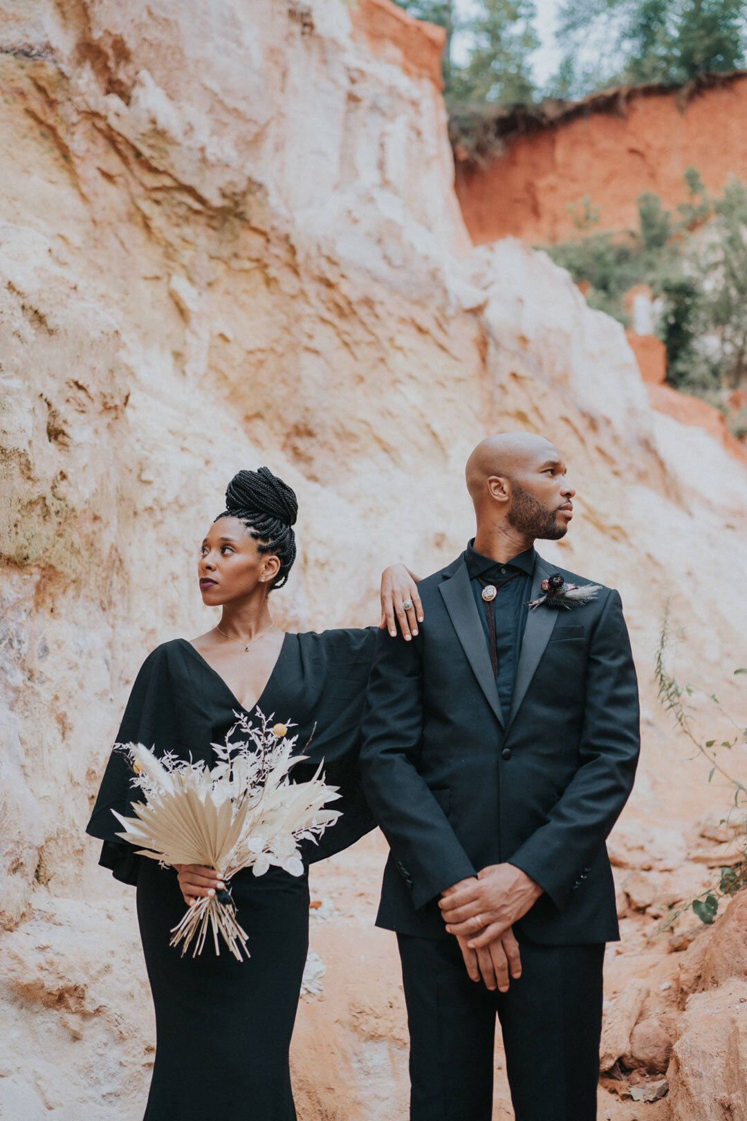 Black couple wearing black outfits holding a white desert bouquet