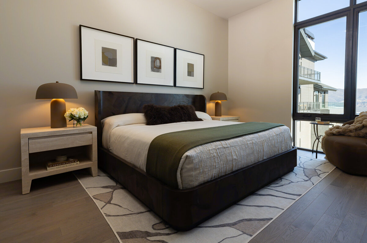 Primary bedroom with moody color palette, layered bedding, and custom artwork in a Park City short-term rental. Designed by Sister Studio