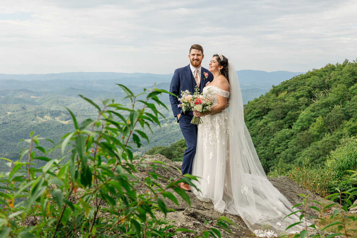 A bride and groom look out a the Blue Ridge Mountains on their wedding day in West Jefferson, NC