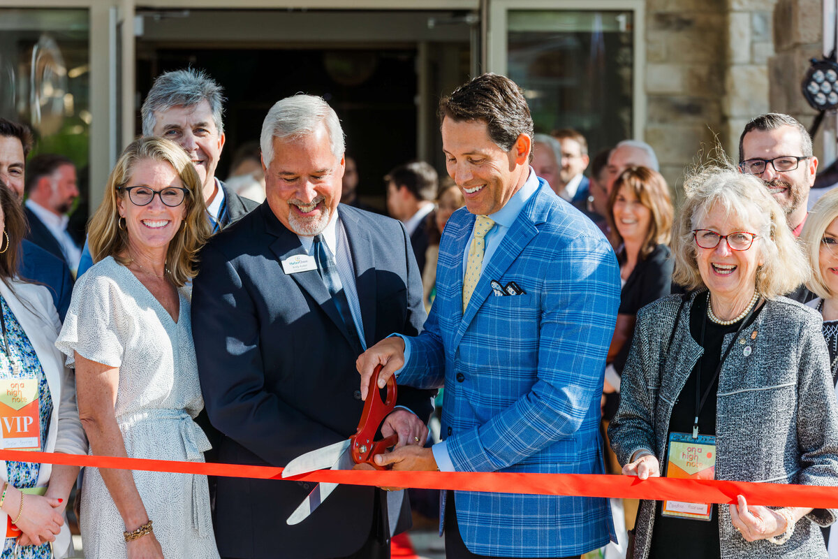 Group of people in business professional clothing smiling at Ribbon cutting ceremony