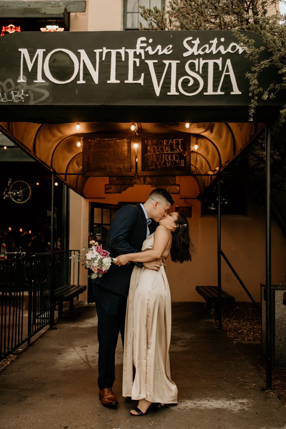 newlyweds kissing in front of a bar in downtown Albuquerque