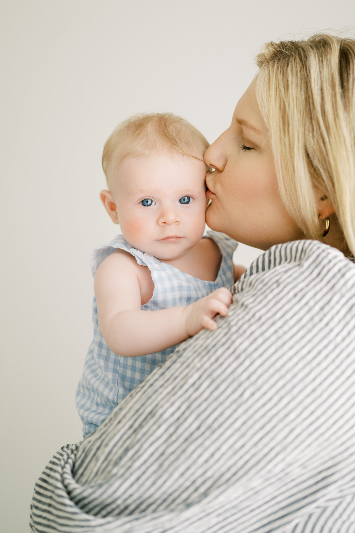 Mom kisses 3 month old baby boy during session with Worth Capturing Photography