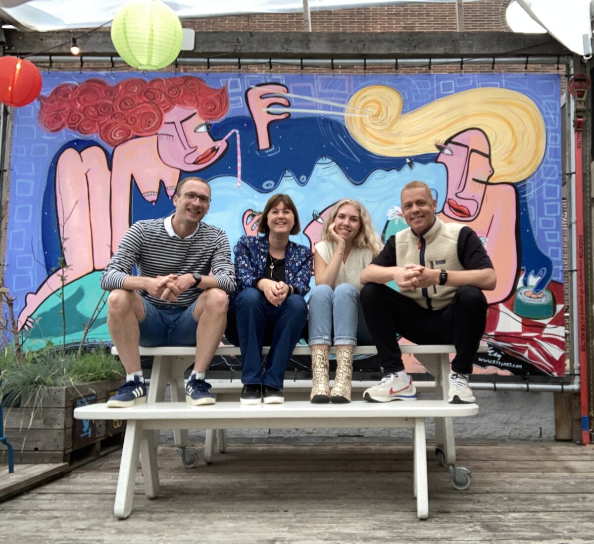 A group of professionals talking in front of a colorful mural, symbolizing collaboration and leadership.