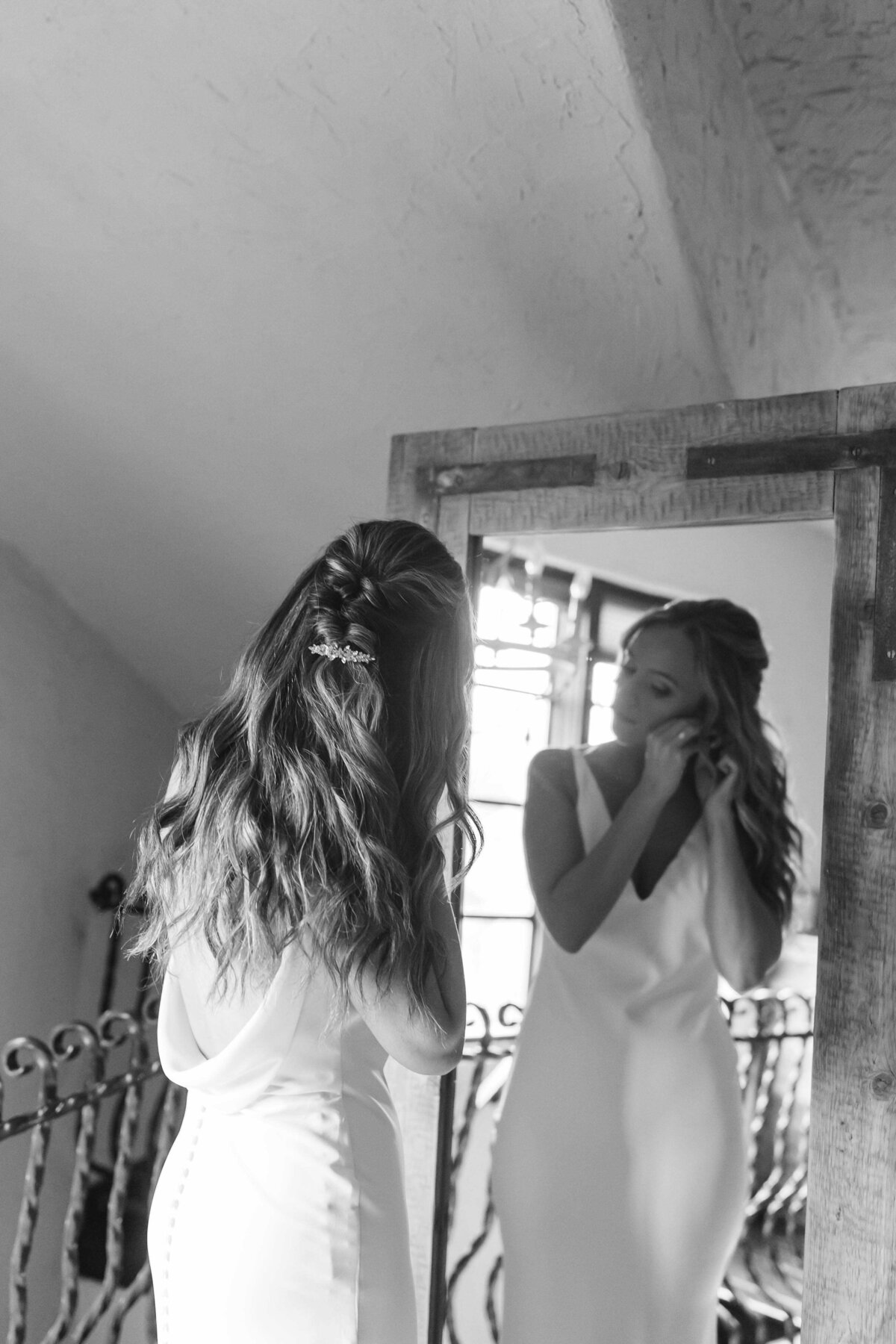 Bride putting in special earrings standing in mirror