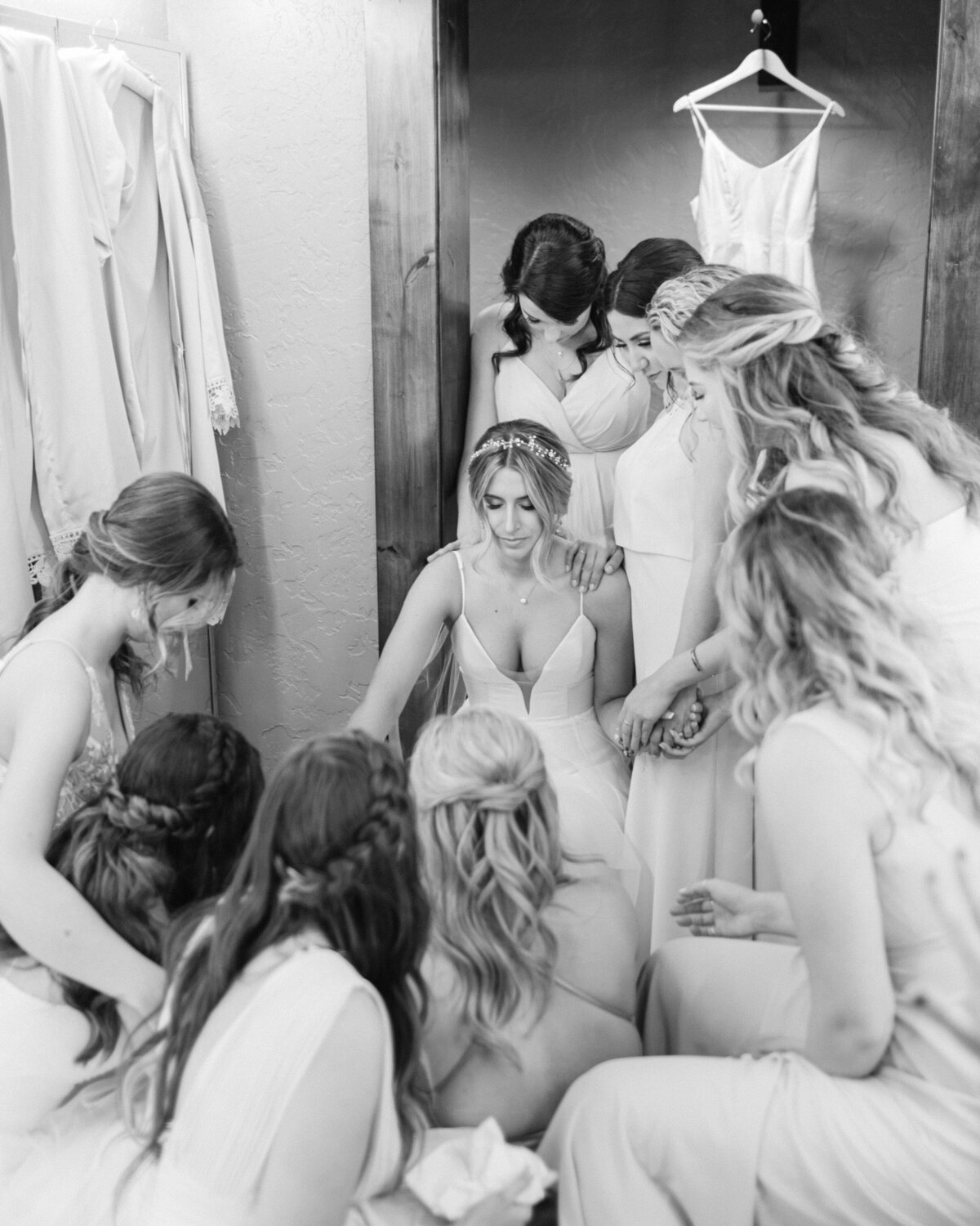 bride and bridesmaids praying over the bride in a black and white photo at swiftwater cellars in suncadia