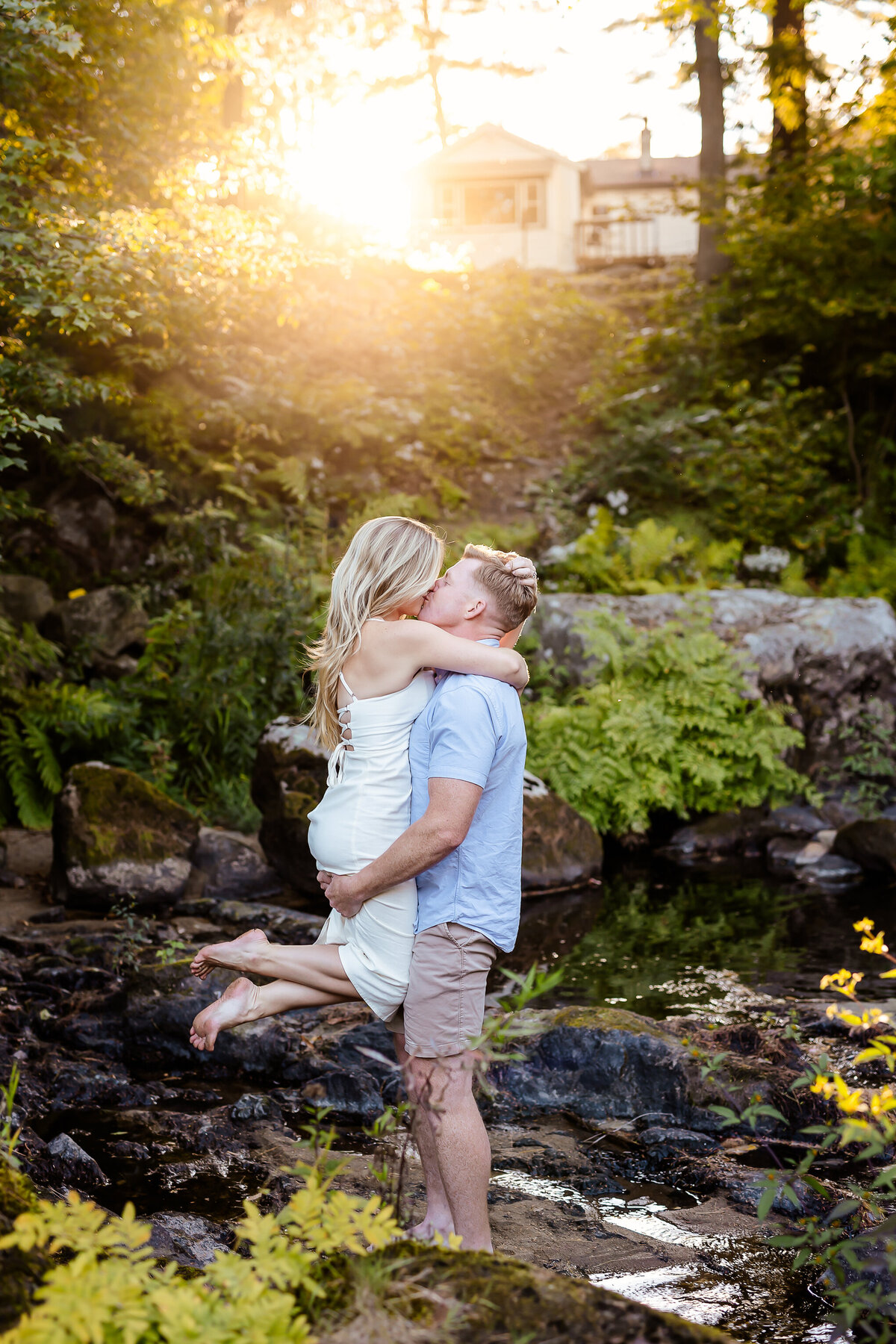 rivers side engagement session with guy lifting girl and kissing her at sunset by nh engagement photographer by lisa smith photography