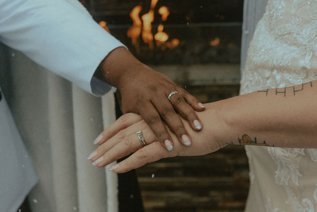 Two hands laid on top of each other showing off wedding rings.