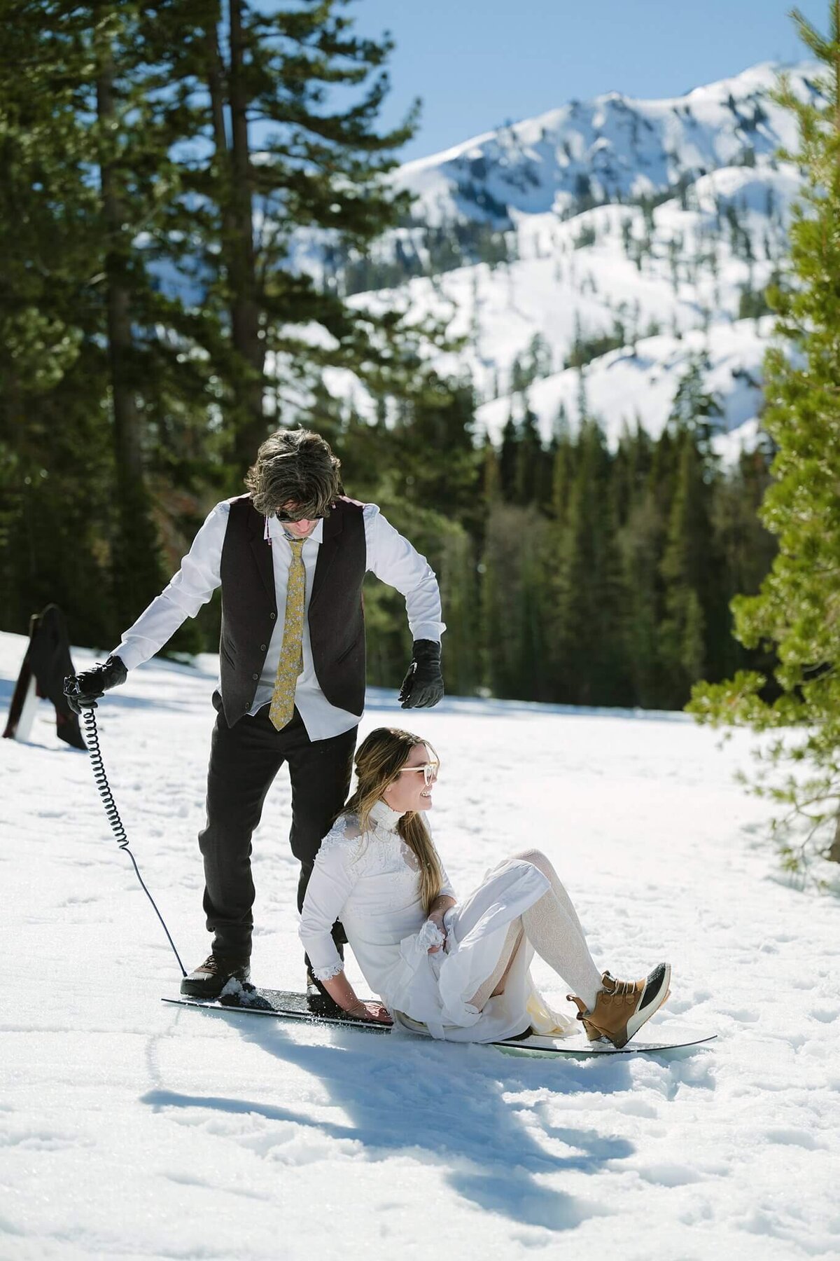 bride and groom on a snowskate together sliding after their elopement ceremony in tahoe