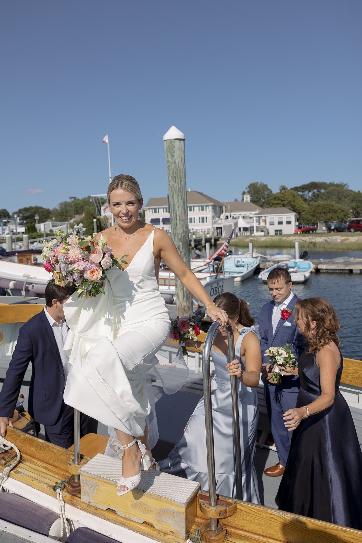 Bride smiles at camera as she arrives by boat for her wedding ceremony.
