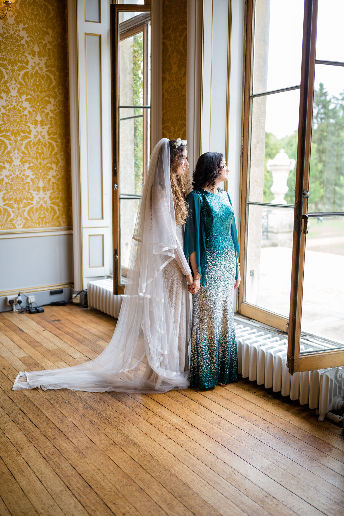 Bride and Mother of Bride stood by an  open window