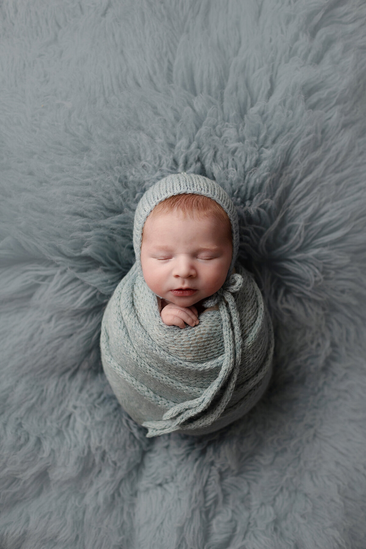 baby boy wrapped in blue for his newborn photos in loveland