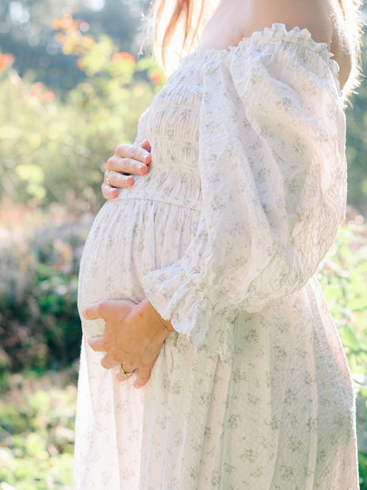 Side view of an expecting mom holding her baby bump.
