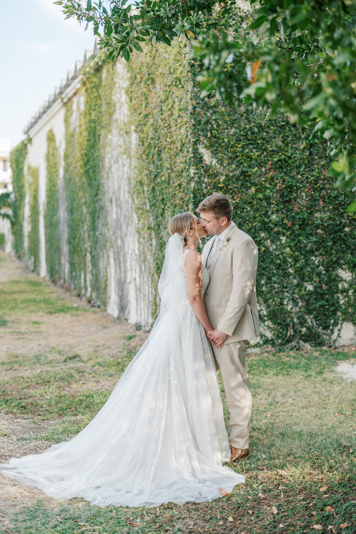 Bride and groom kiss beside ivy-covered wall during Cancun wedding, photo by Philadelphia photographer.