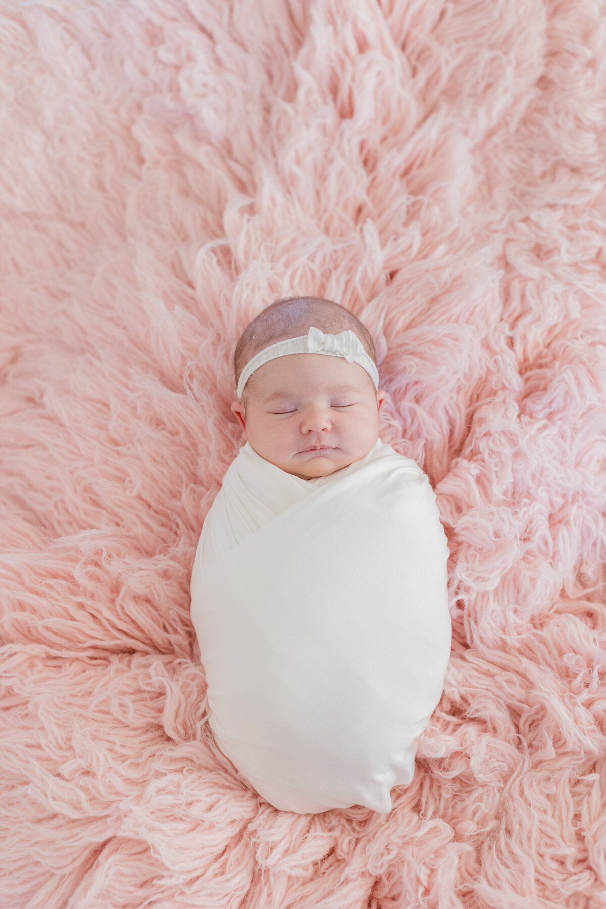 A baby laying on a fuzzy pink blanket