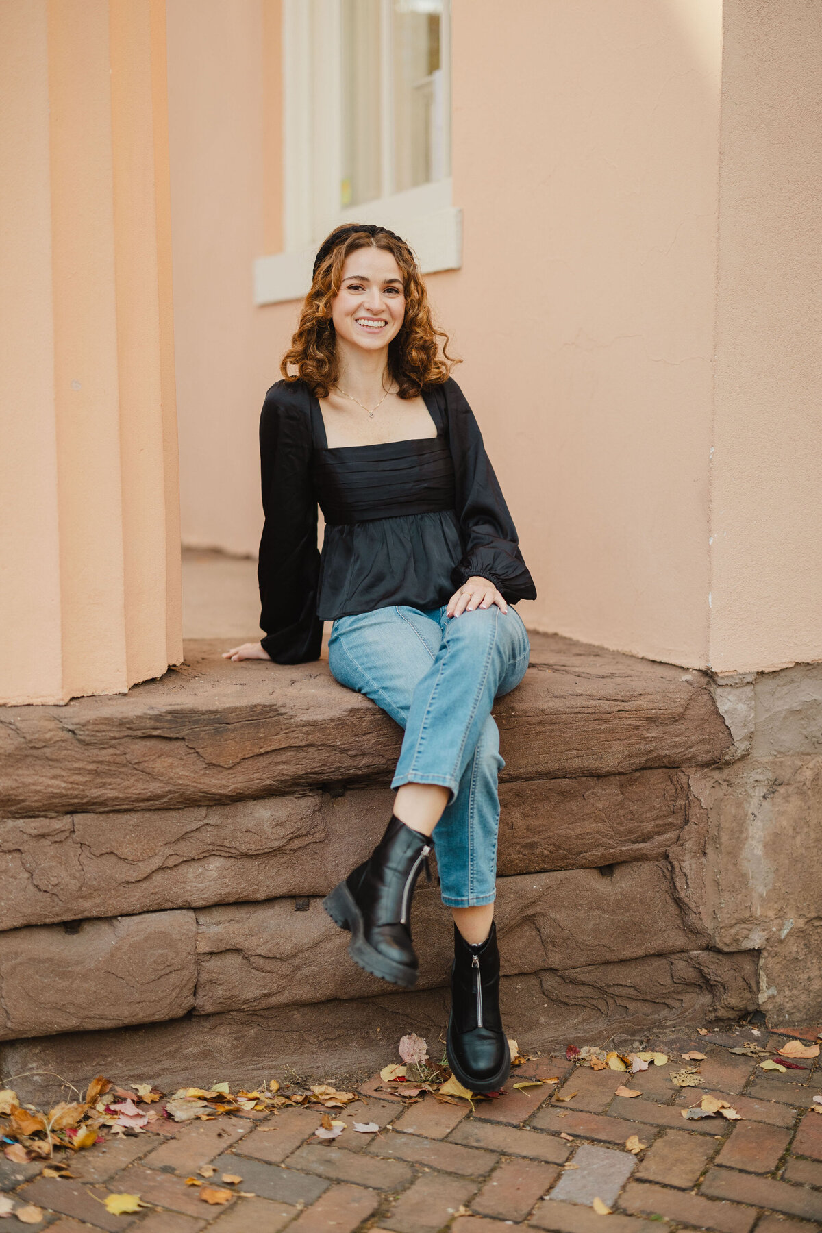 A person sits with legs crossed on a rock stoop.