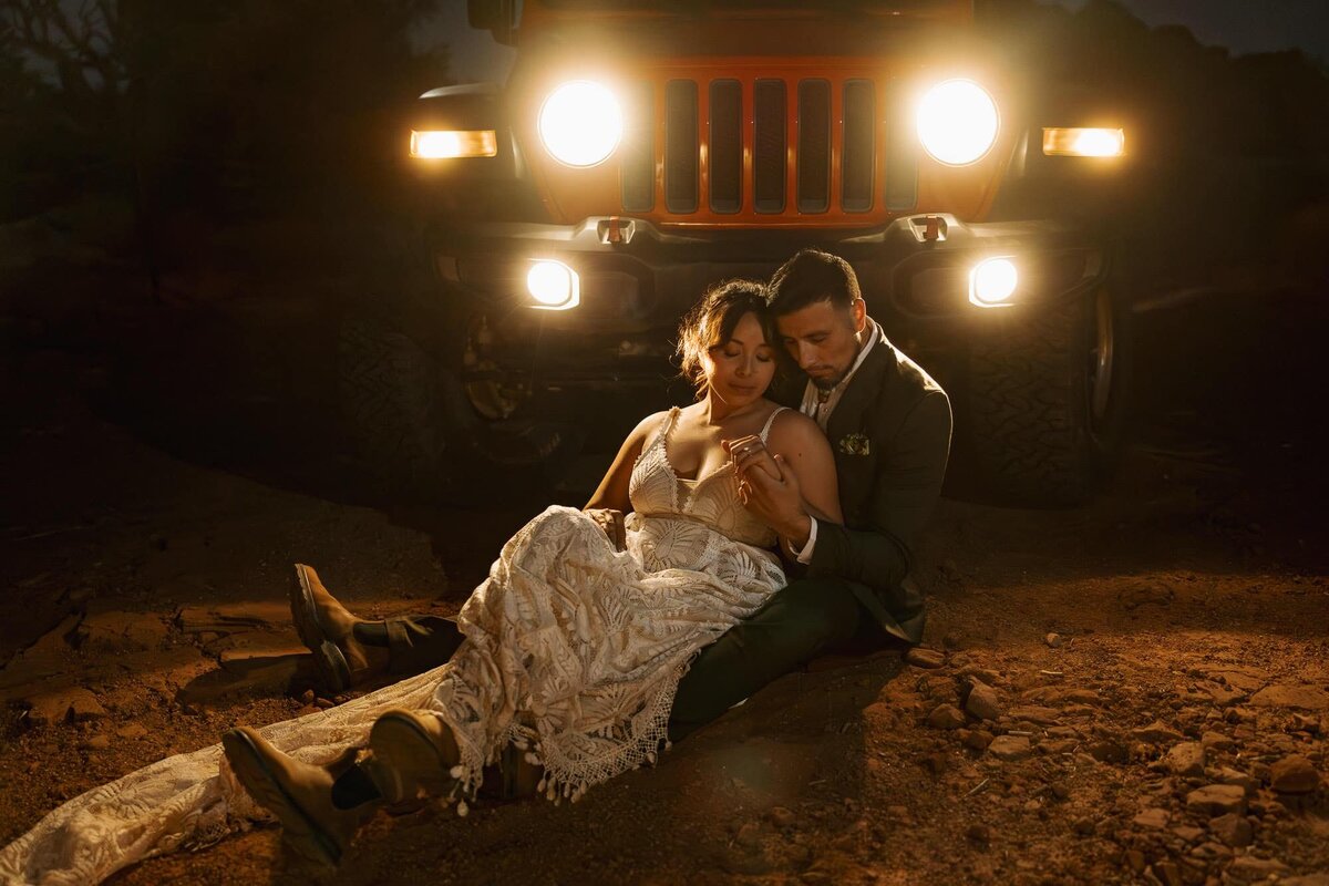 A couple Sits in front of the headlights of their jeep as they celebrate the end of their elopement day at Marlboro Point.