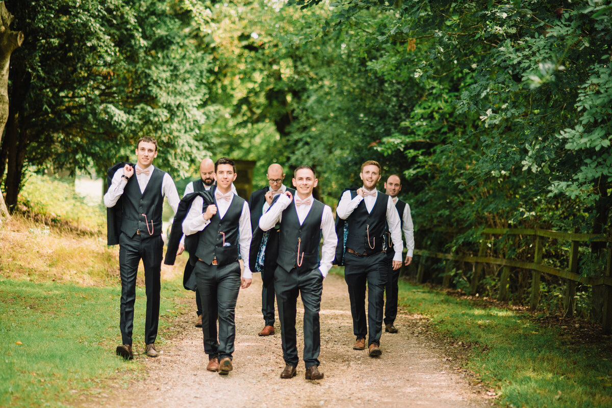 A groom and groomsmen walking down a dirt path in a woodland area taken by London Wedding Photographer Liberty Pearl