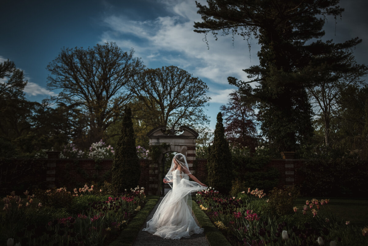 A couple standing at the end of a long walkway as they hold hands.