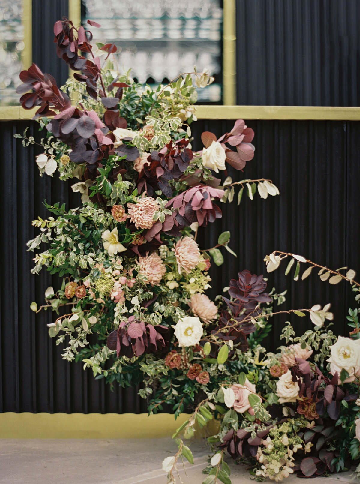 Moody welcome party for fall wedding weekend. Tented reception for outdoor wedding reception at Blackberry Farm. Moody floral design with colors of deep magenta, mauve, eggplant, blush, and natural greens. Rich tones with roses, mums, and smokebush foliage. Romantic candle light and large trees create a magical setting for a welcome party. Destination wedding at Blackberry Farm. Design by Rosemary & Finch Floral Design in Nashville, TN.