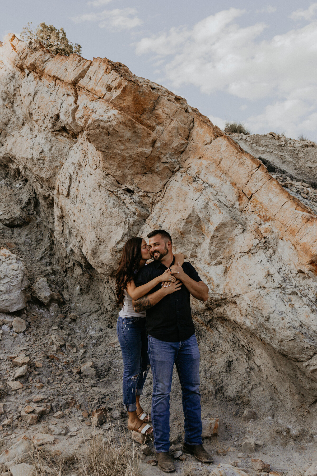 woman hugging her fiancé in front of a unique rock structure