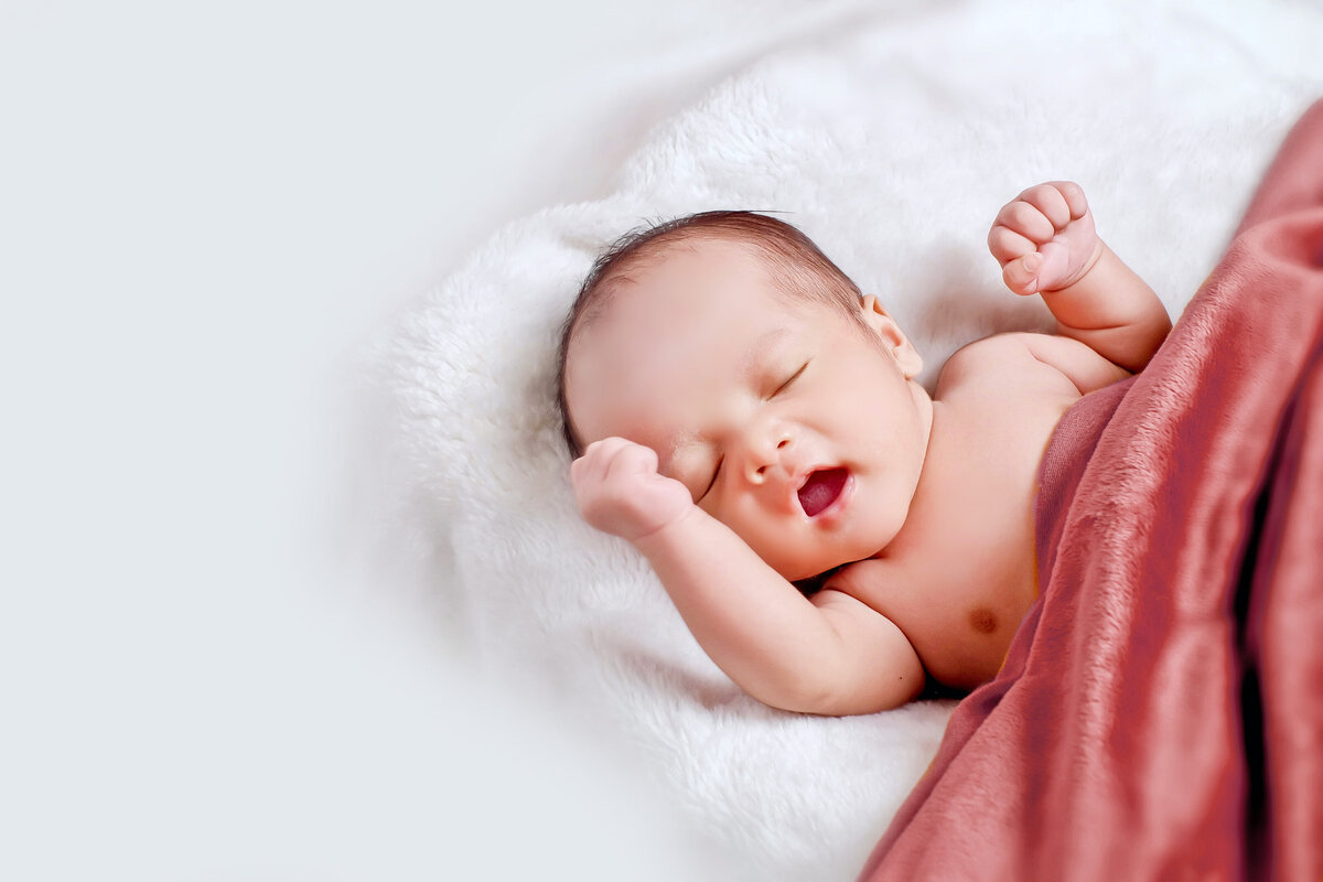 Newborn baby sleeping on a white throw