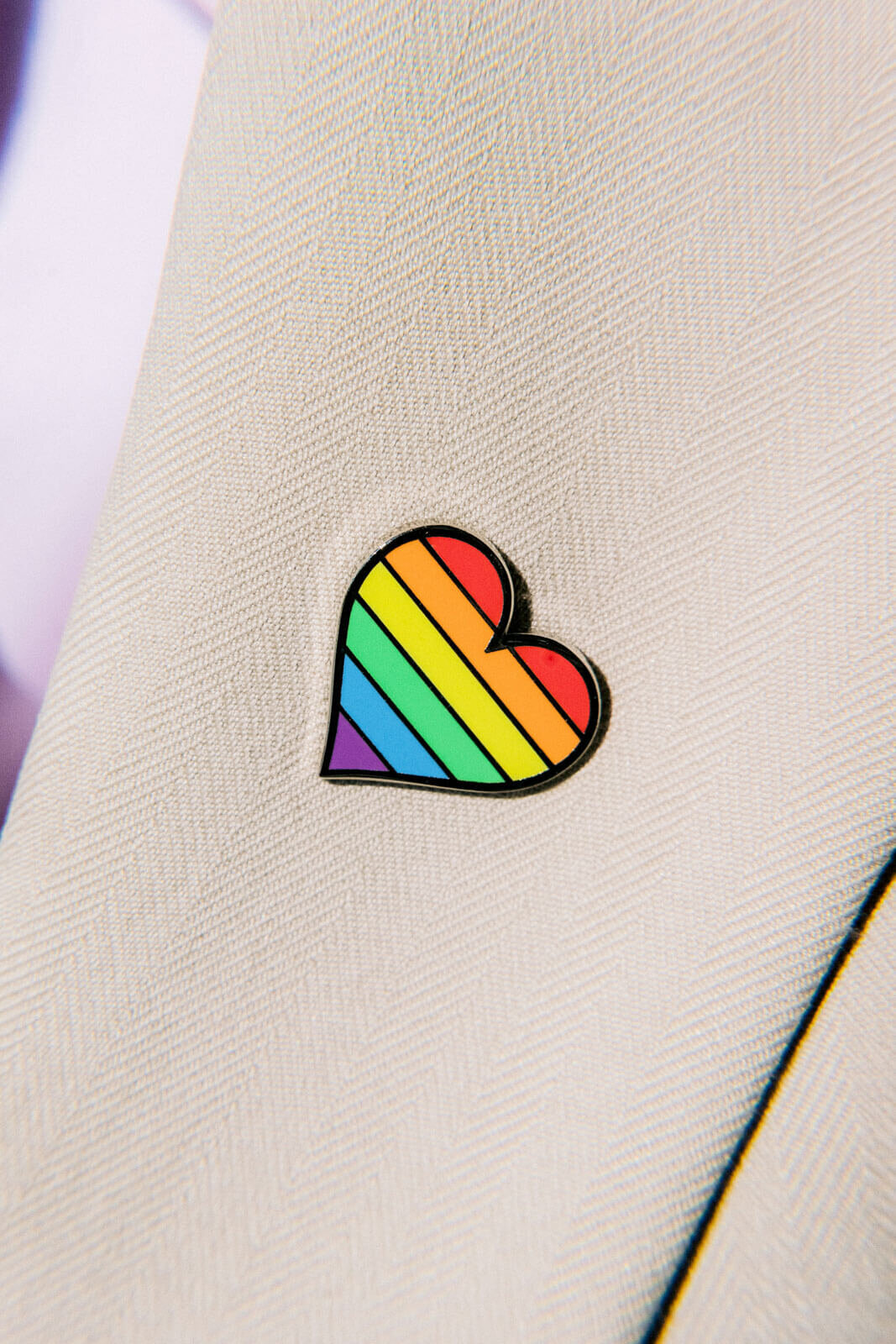 A multi-colored heart-shaped pin on the groom's suit. NYC City Hall Elopement Image by Jenny Fu Studio