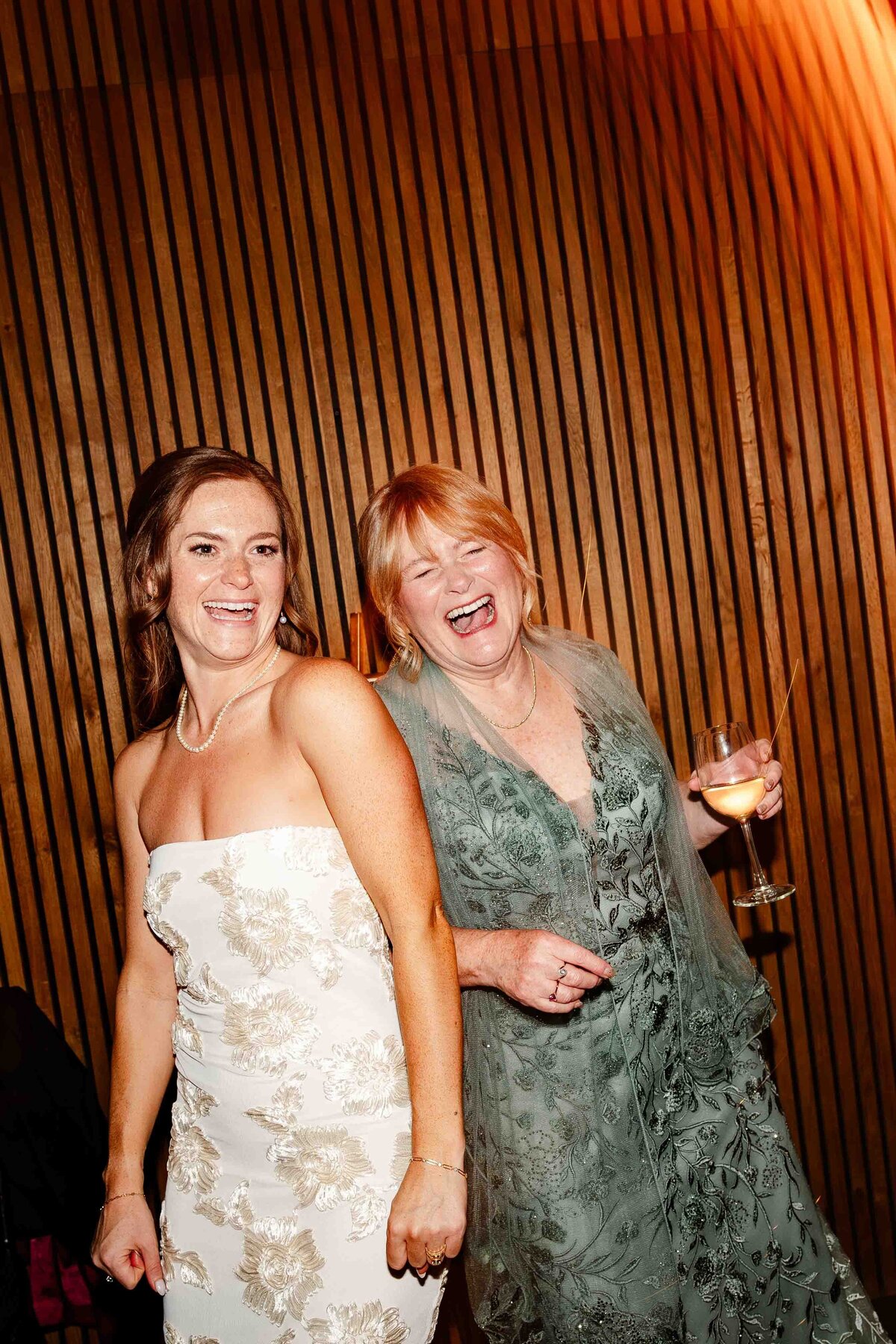 Mom and bride laugh on dance floor 