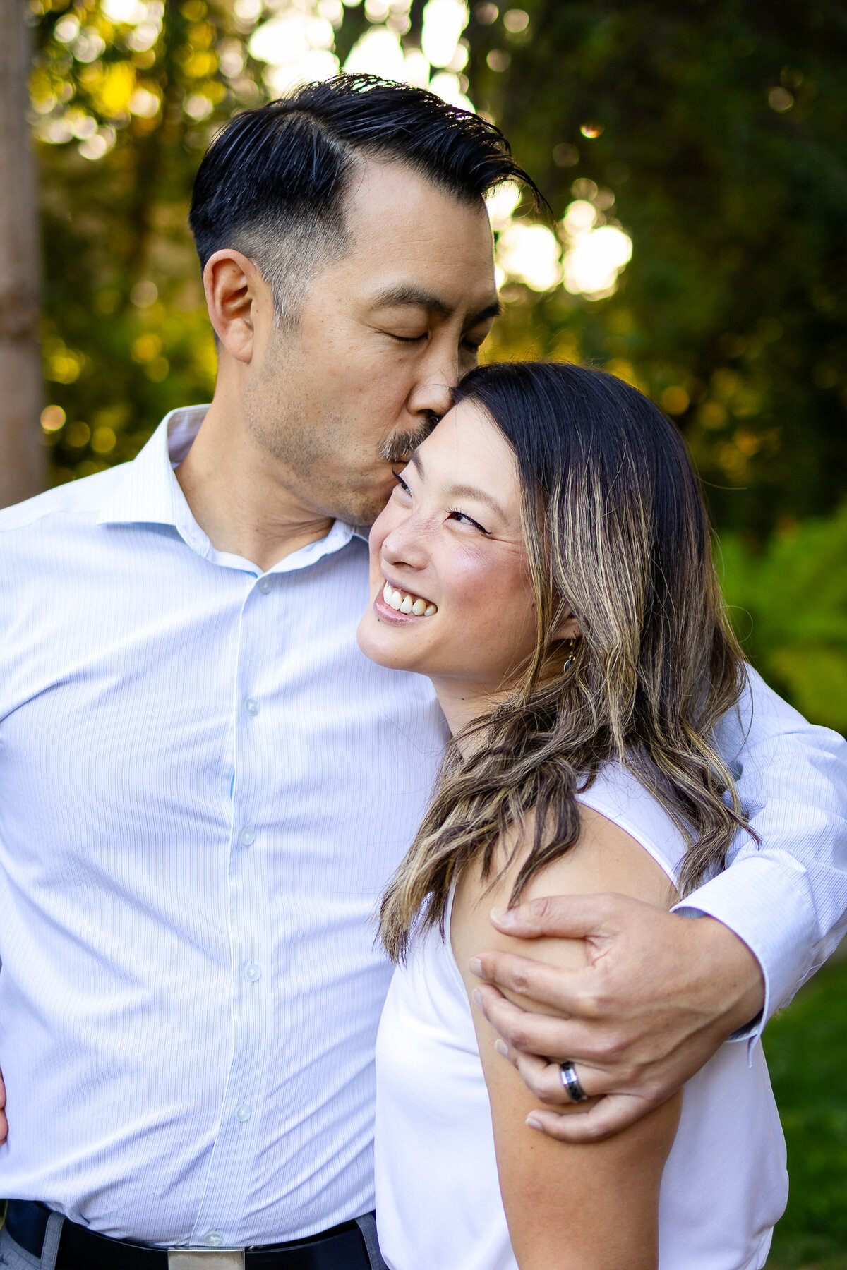 Man kissing woman’s forehead during golden hour