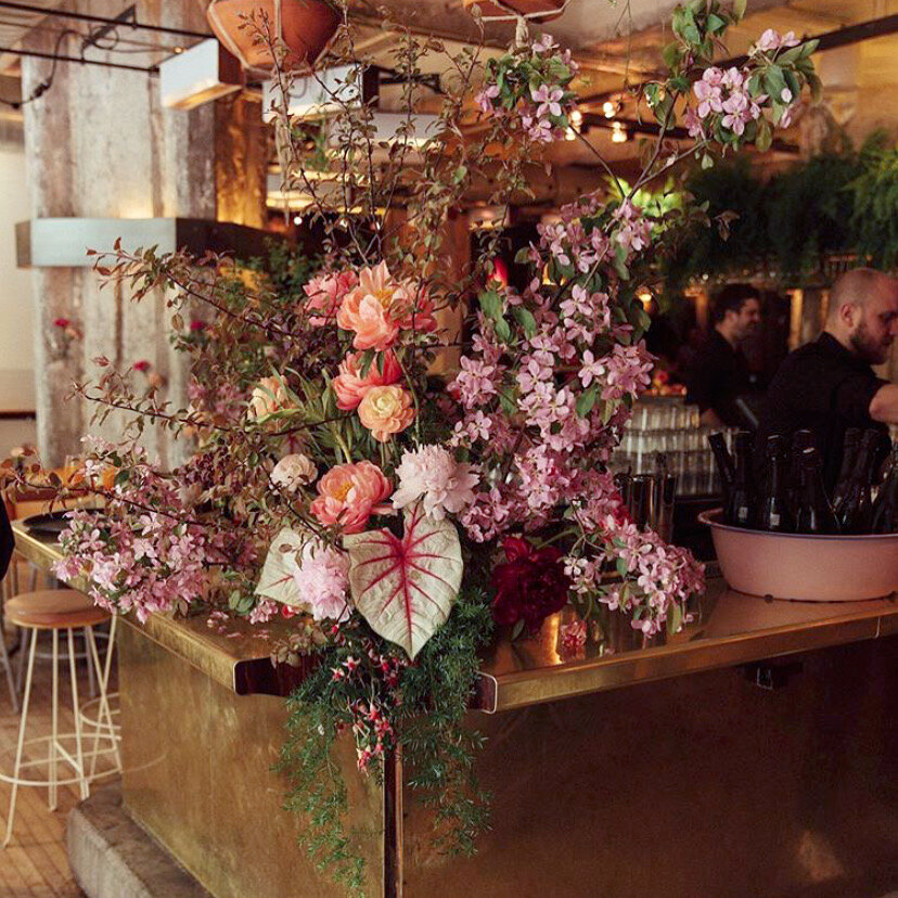 A marble counter at Bar Furco is topped with a bright garden arrangement at a Montreal wedding.