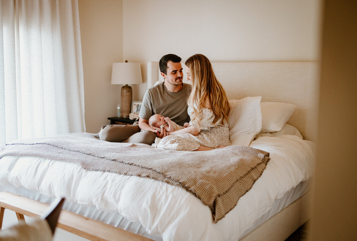 Mom and dad holding newborn in bed