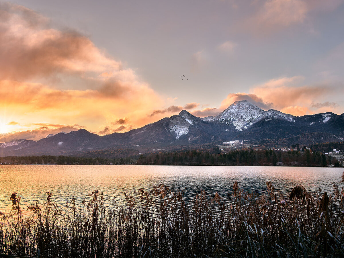 Herbstlicher Sonnenaufgang am Faaker See mit Blick auf den schneebedeckten Mittagskogel – besondere Lichtstimmung in den Alpen eingefangen von Fotograf Atelier Schulte – Spezialist für stimmungsvolle Landschaftsfotografie in Österreich.
