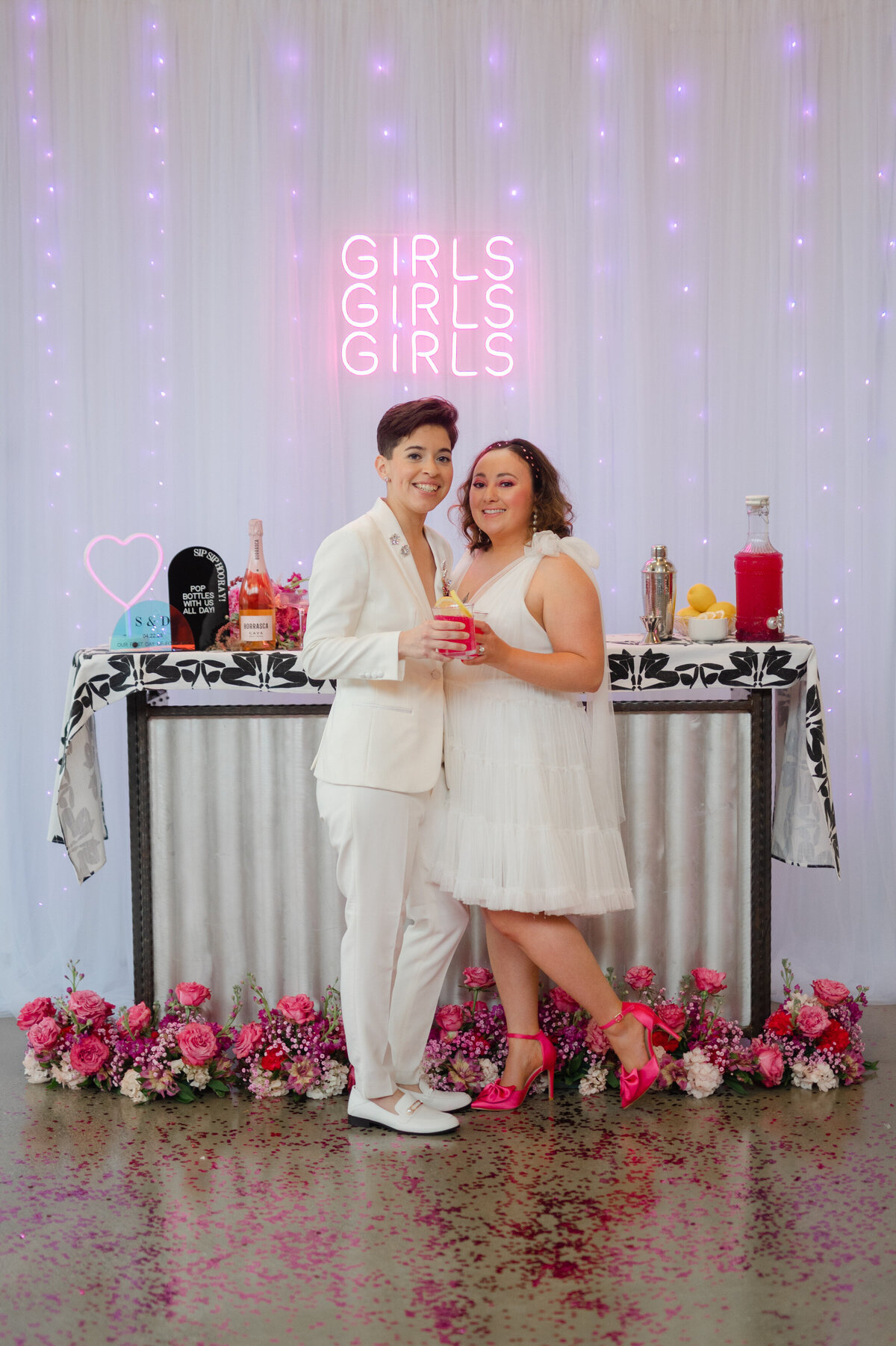 Two brides cheersing glasses at the wedding bar