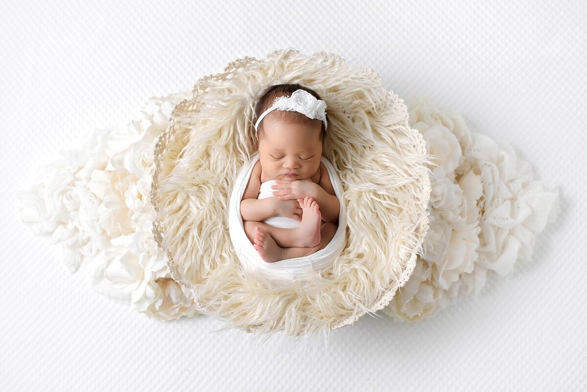 On location Vancouver newborn photos of Asian baby girl in all white basket with flowers