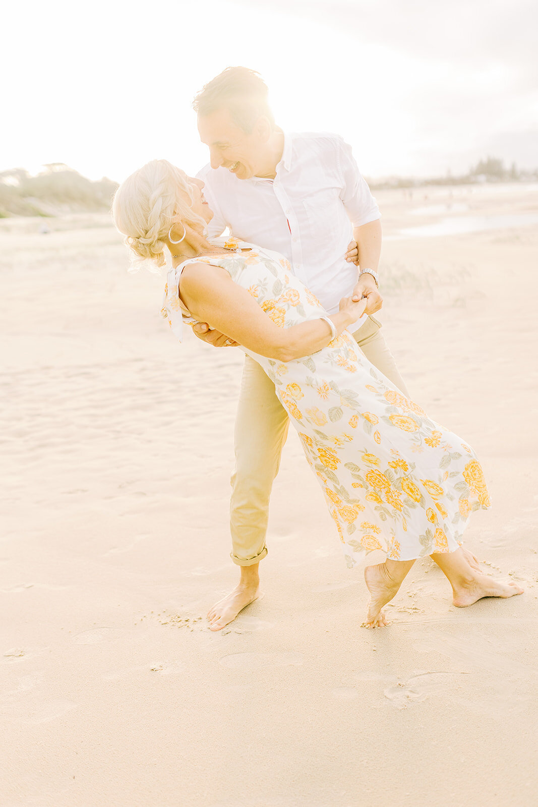 husband dipping wife dancing on beach