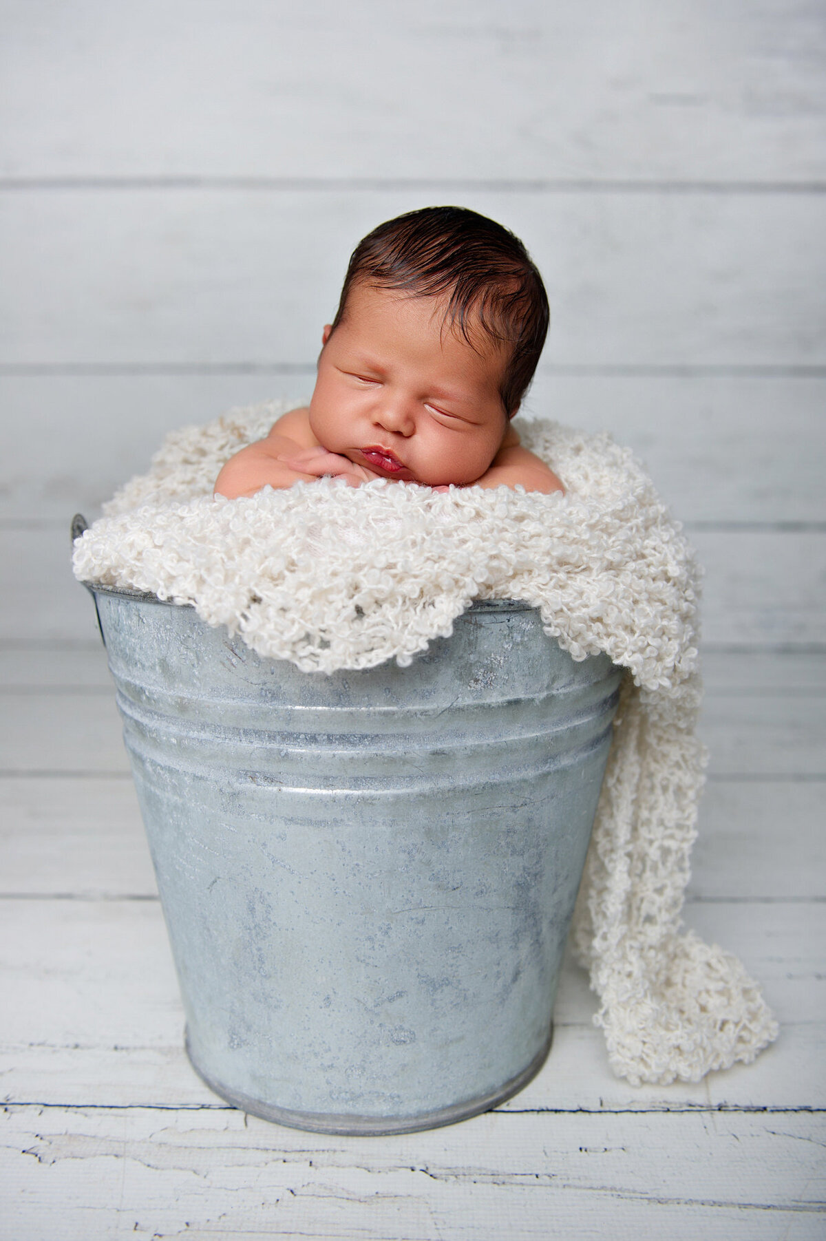 baby boy photographed in a tin bucket