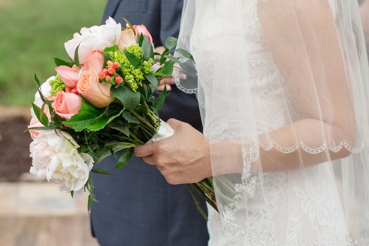 bride holding bouquet of peach roses arm in arm with father and scalloped veil down aisle at wedding in Boerne Texas by Firefly Photography